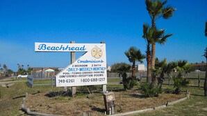 A sign for Beachhead Condominiums with amenities like 2 bedrooms, 2 baths, daily, weekly, monthly parking, pool, tennis, covered parking, conference, and reception rooms. - Fun in the Sun 102BH (Port Aransas)