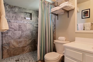 A bathroom with a shower, toilet, and sink. - The Shell House 1120SS (Port Aransas)
