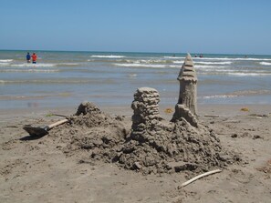 A sandy beach with a sandcastle and a shovel. - Key Lime Cottage 19RP (Port Aransas)