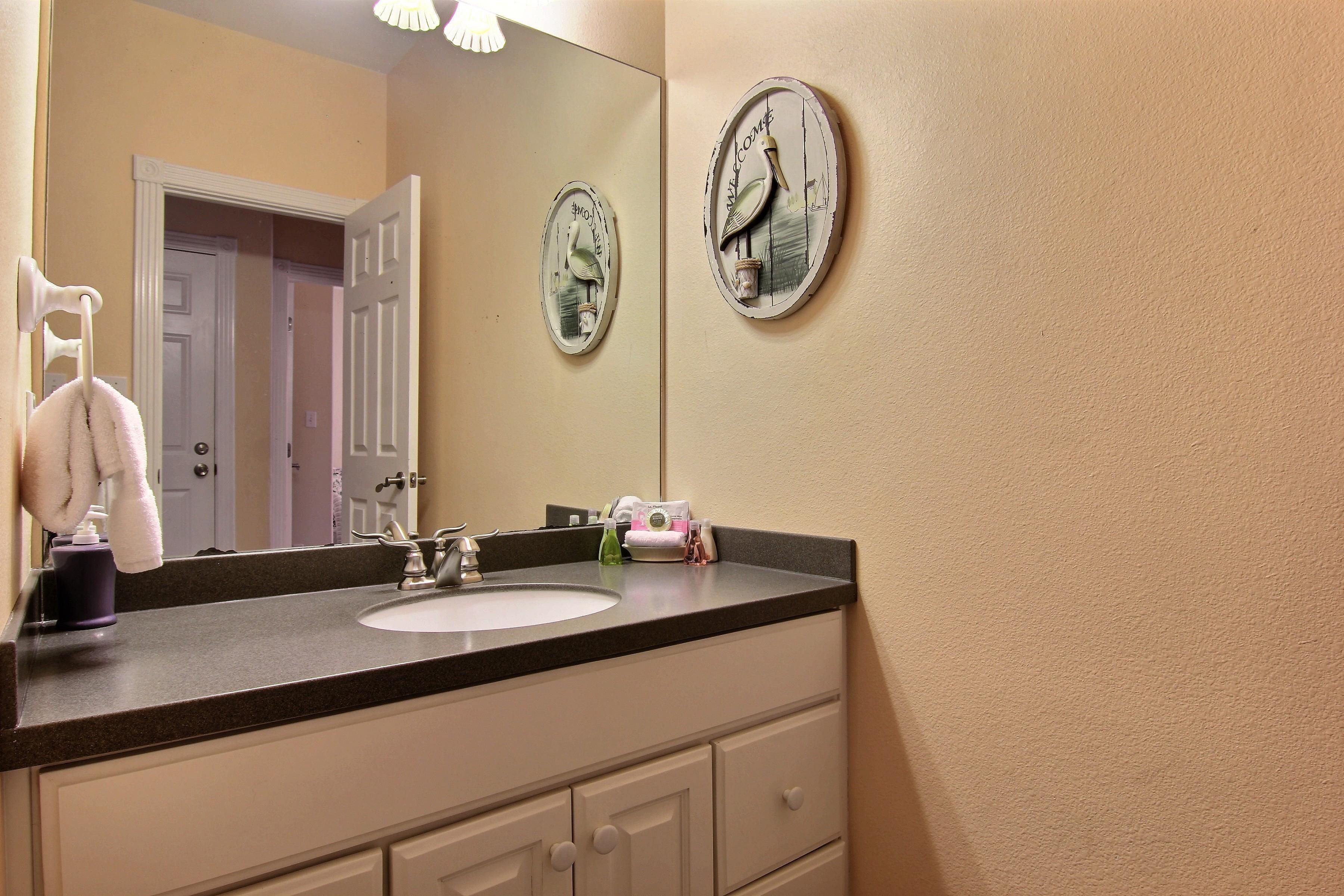 A bathroom with a sink, mirror, and two wall clocks.