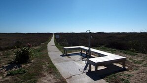 A clear sky with a pathway leading to a bench area with picnic tables. - Turtle s Pace SIV5 (Port Aransas)