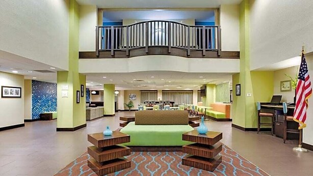 A spacious lobby with a central seating area, a balcony, and an American flag.