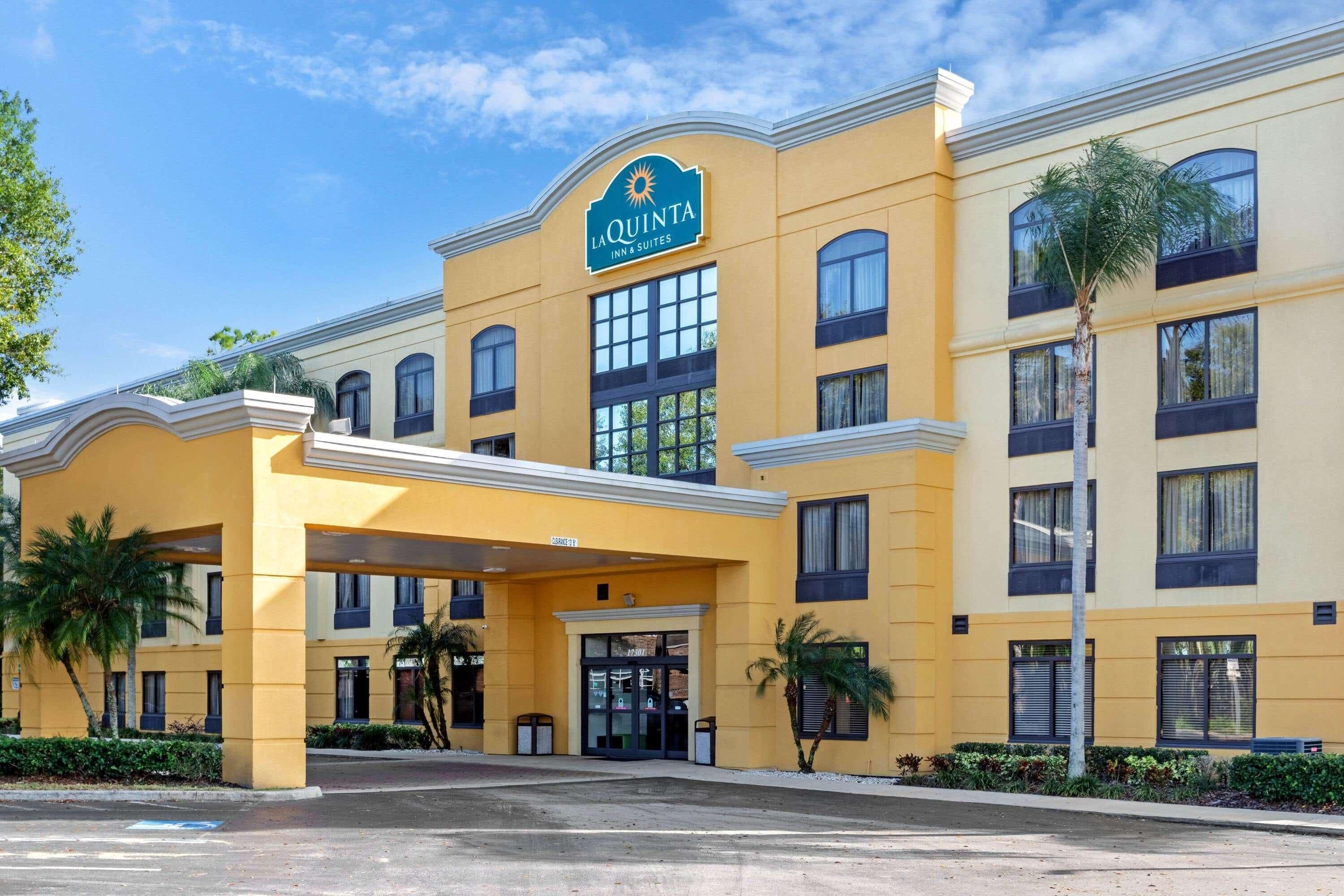 Un hotel con fachada amarilla, cielo despejado y palmeras.