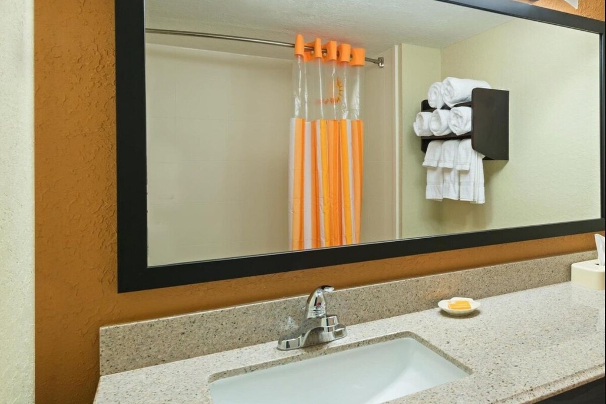 Een badkamer met een wastafel, spiegel, handdoekrek en douchegordijn.