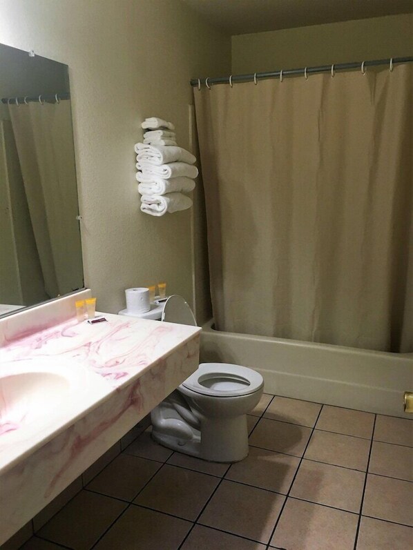 A bathroom with a marble sink, a toilet, a shower curtain, and a towel rack. - Mission Motel Lynwood (Lynwood)