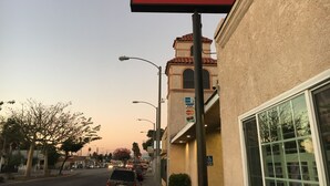 Une vue de rue avec une enseigne indiquant le « Mission Motel », un bâtiment à la façade beige et un ciel dégagé.