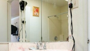 A bathroom with a marble sink, a large mirror, and a hairdryer mounted on the wall. - Mission Motel Lynwood (Lynwood)