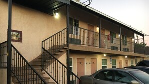 Un motel à deux étages, doté d’un escalier, de chambres numérotées et d’une voiture garée devant.