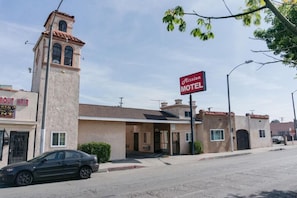A motel with a tower, a signboard, and a car parked in front. - Mission Motel Lynwood (Lynwood)
