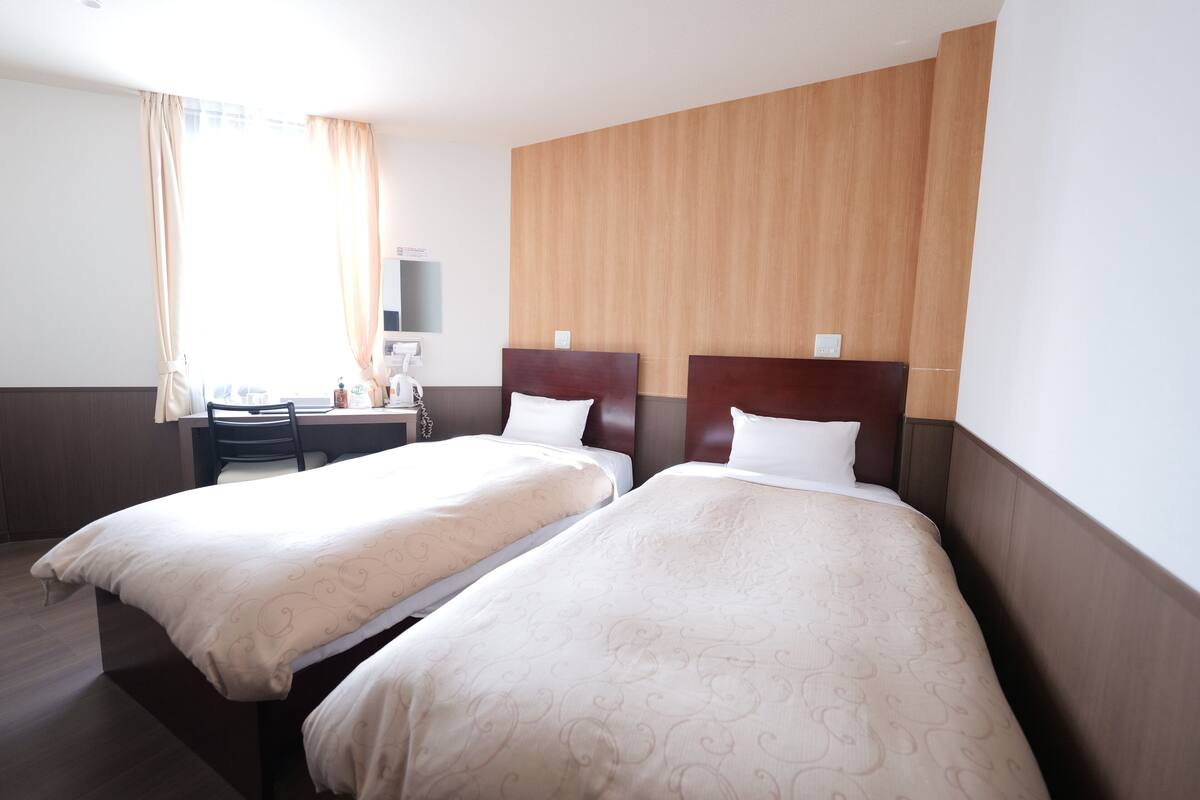 Una habitación de hotel con dos camas individuales, un escritorio y una silla.