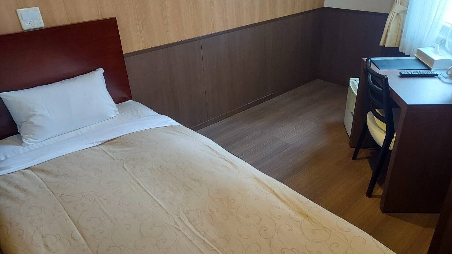 A hotel room with a bed, a desk, and a chair.