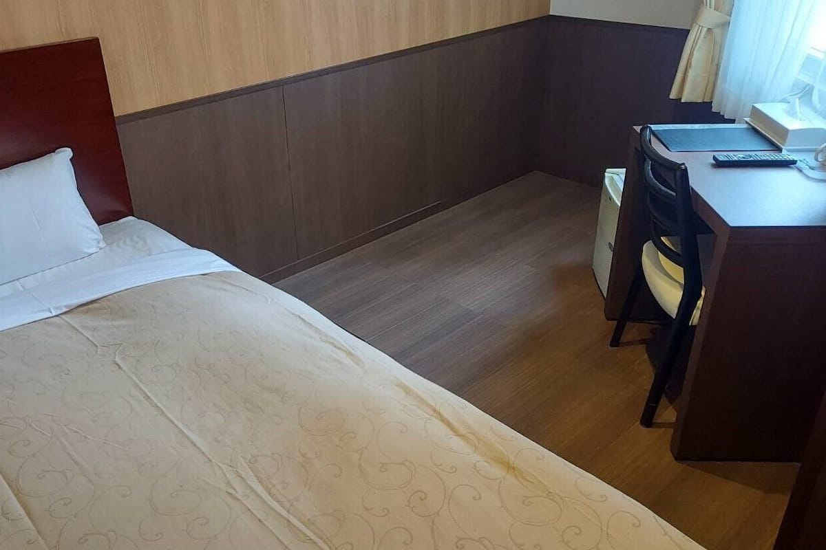 Una habitación de hotel con una cama, un escritorio y una silla.