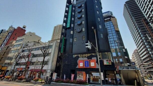 Un edificio moderno con varios pisos, amplias ventanas y una entrada destacada con señalización.