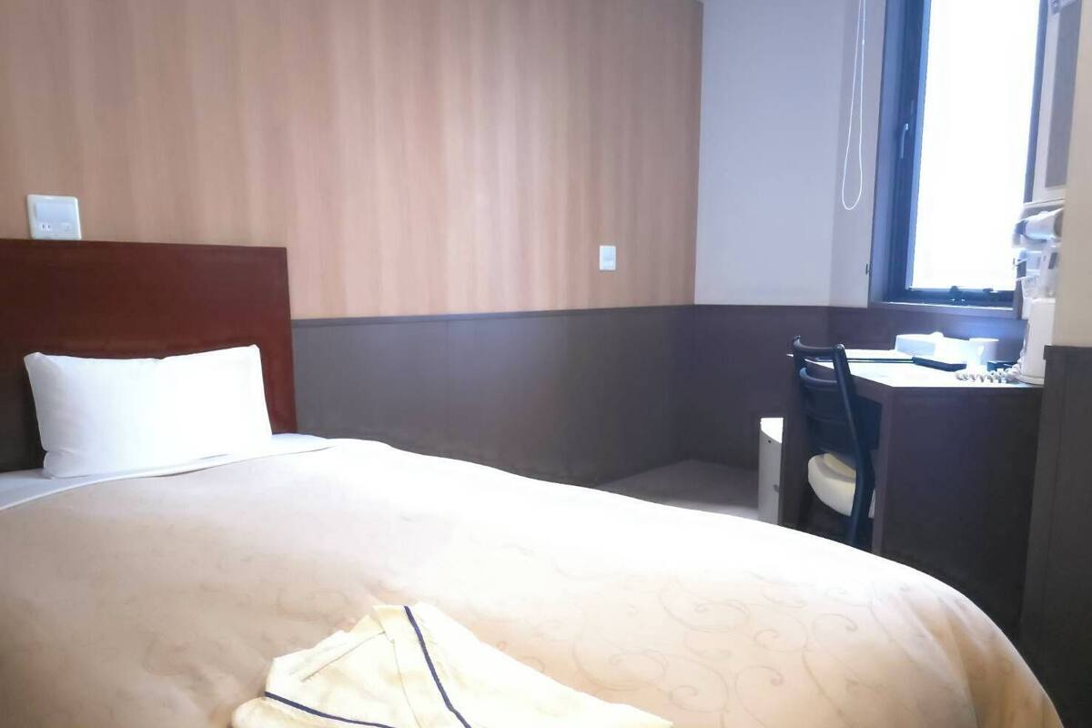 Una habitación de hotel con cama, escritorio y ventana.