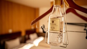 Botellas de refrescos para la ducha colgadas de un perchero de madera en una habitación de hotel.