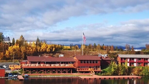 A lakeside lodge with a dock, a red building with a balcony, and an American flag. - Mat-Su Resort (Wasilla)