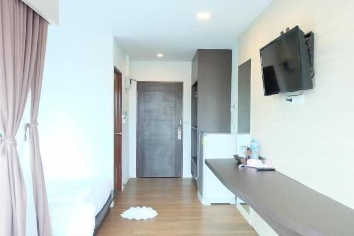 A hallway with a wooden floor, a door, a flat-screen TV mounted on the wall, and a counter with a flat surface.