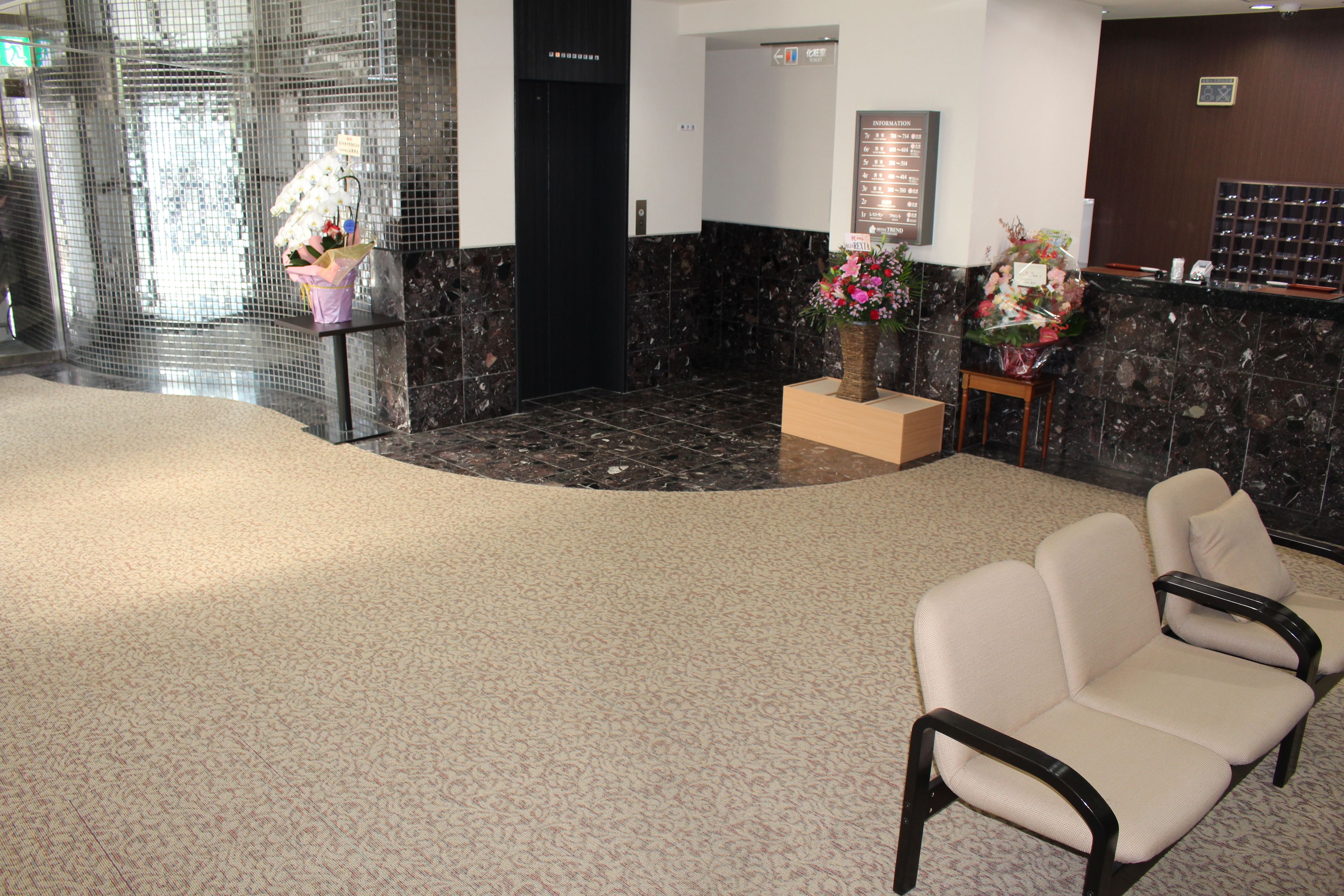 A lobby with a reception desk, a seating area, and a decorative flower arrangement.