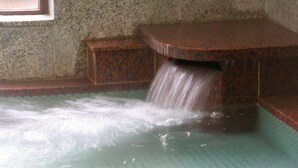 Un muro de piedra con una fuente de agua, que incluye una cascada pequeña y una piscina.