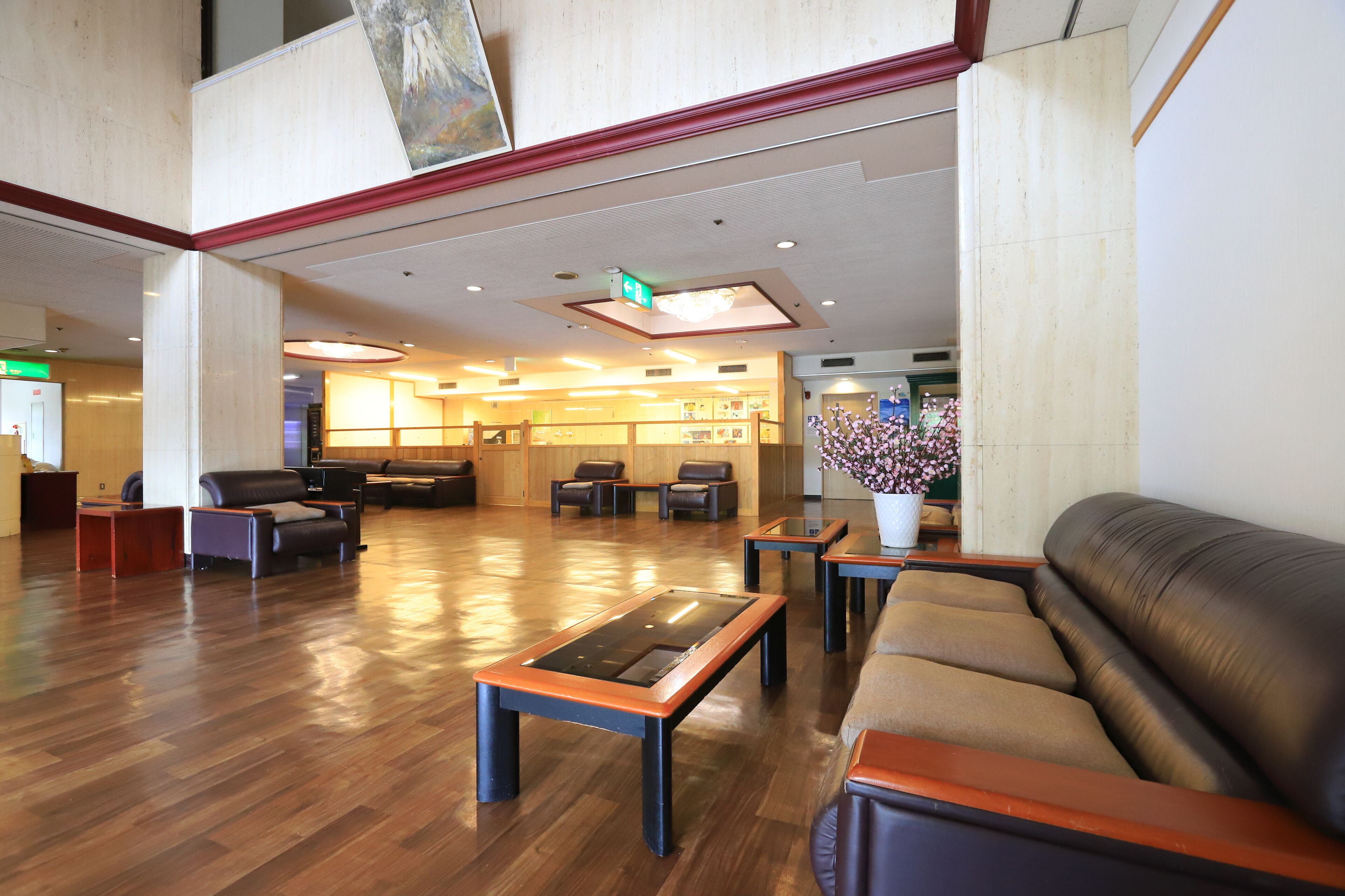 A spacious lobby with a high ceiling, wooden flooring, and a variety of seating options including sofas and chairs.