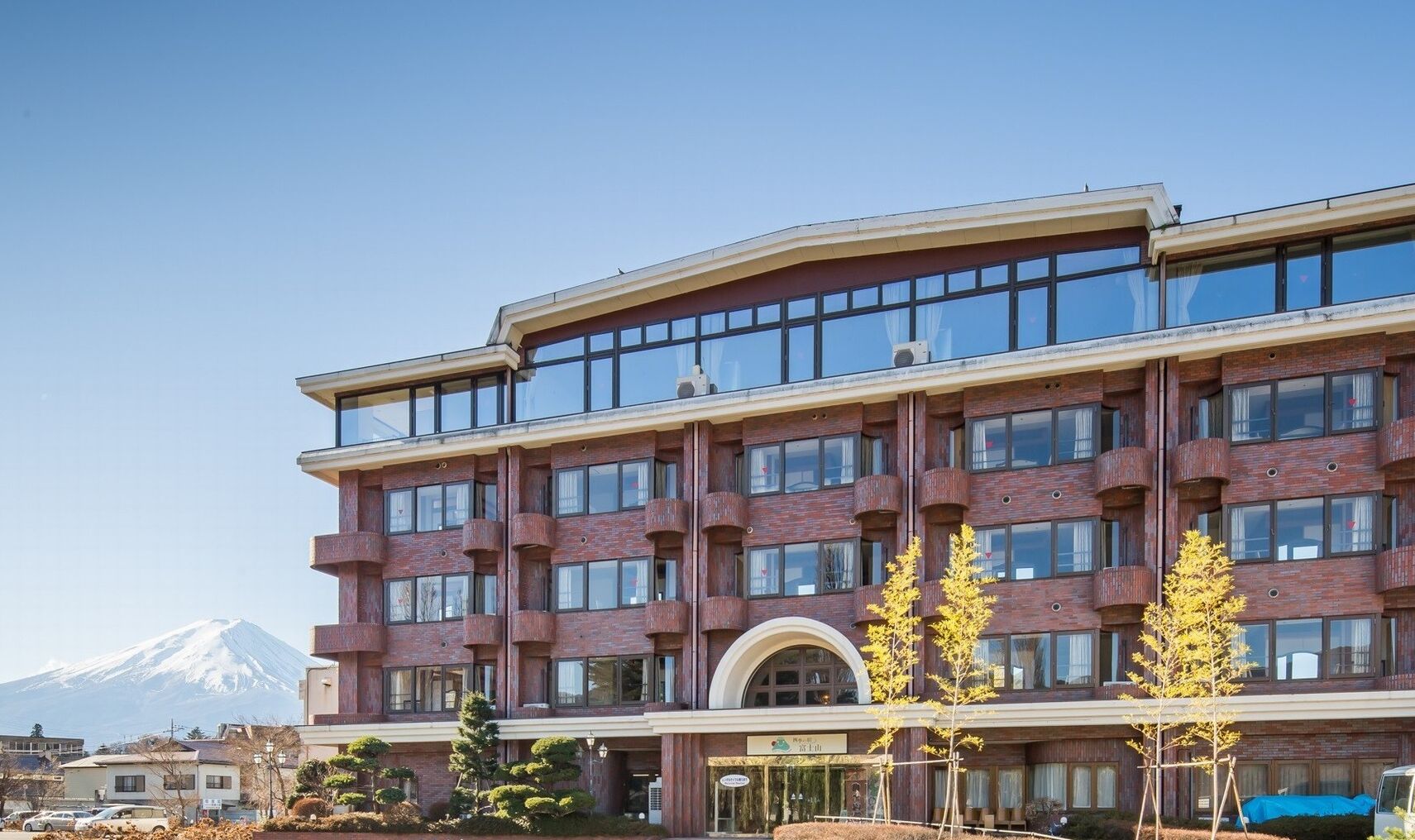 A multi-story hotel with a prominent entrance, large windows, and a mountain in the background.