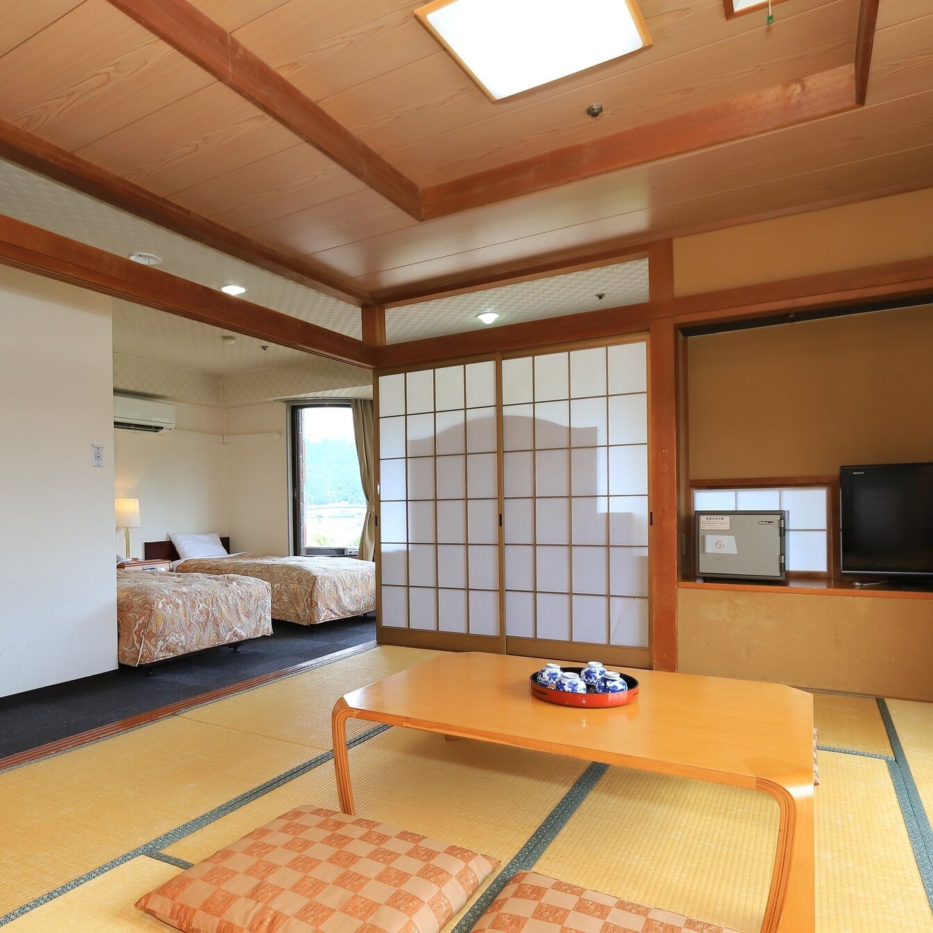 Een traditionele Japanse kamer met tatami vloerbedekking, een lage tafel met een schaal, en een televisietoestel op een standaard.