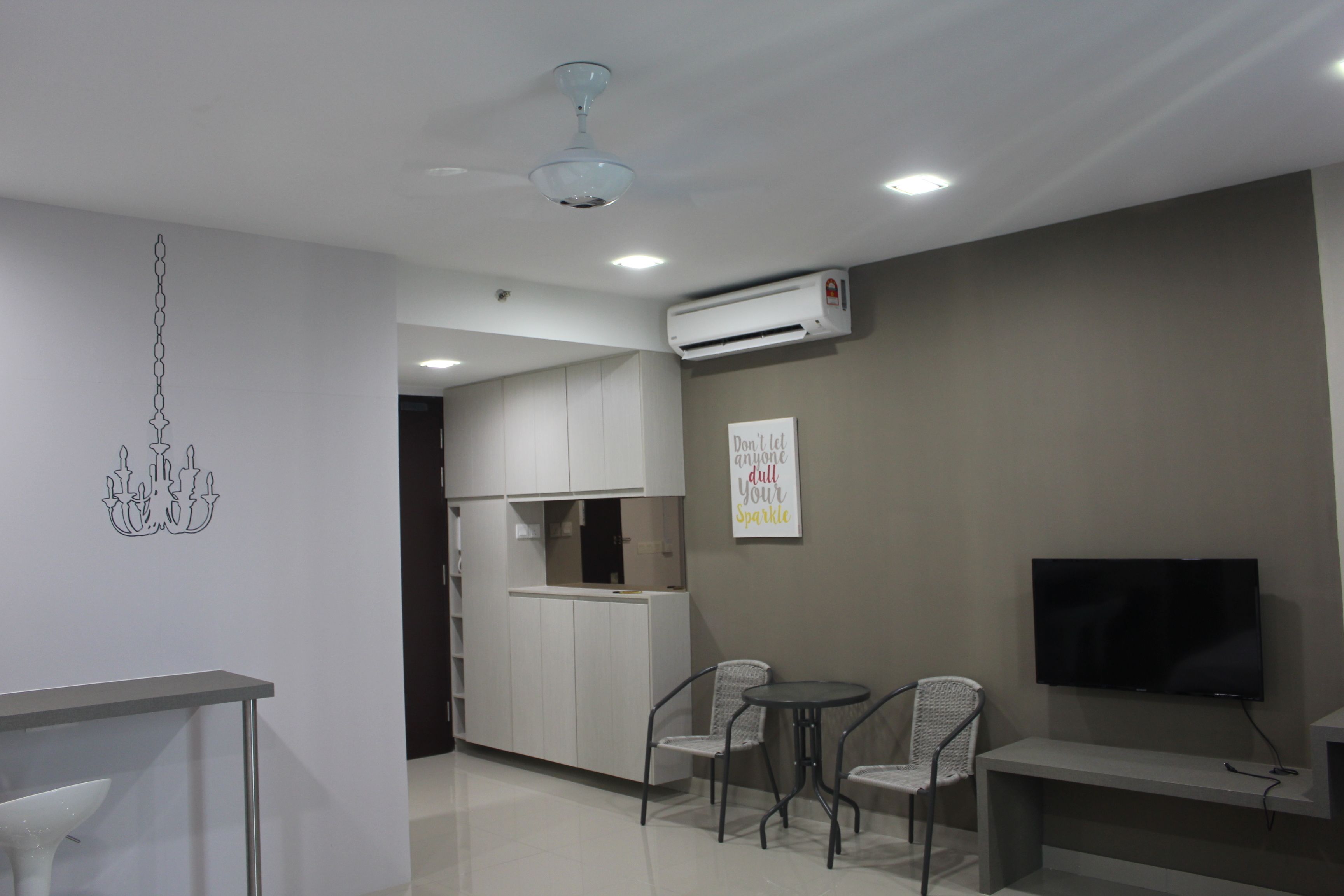 A modern living room with a dining area, a TV mounted on the wall, and an air conditioning unit.