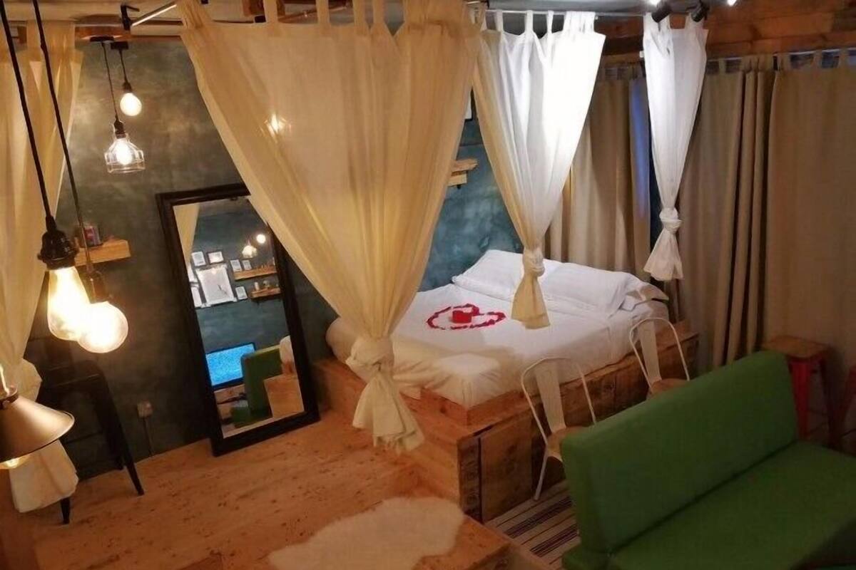 Une chambre à coucher avec un lit, une chaise verte et une table en bois.