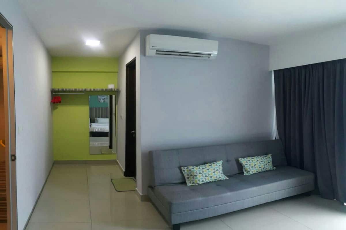 Un salon moderne avec un canapé gris, deux coussins à motifs et un grand appareil de climatisation fixé au mur.