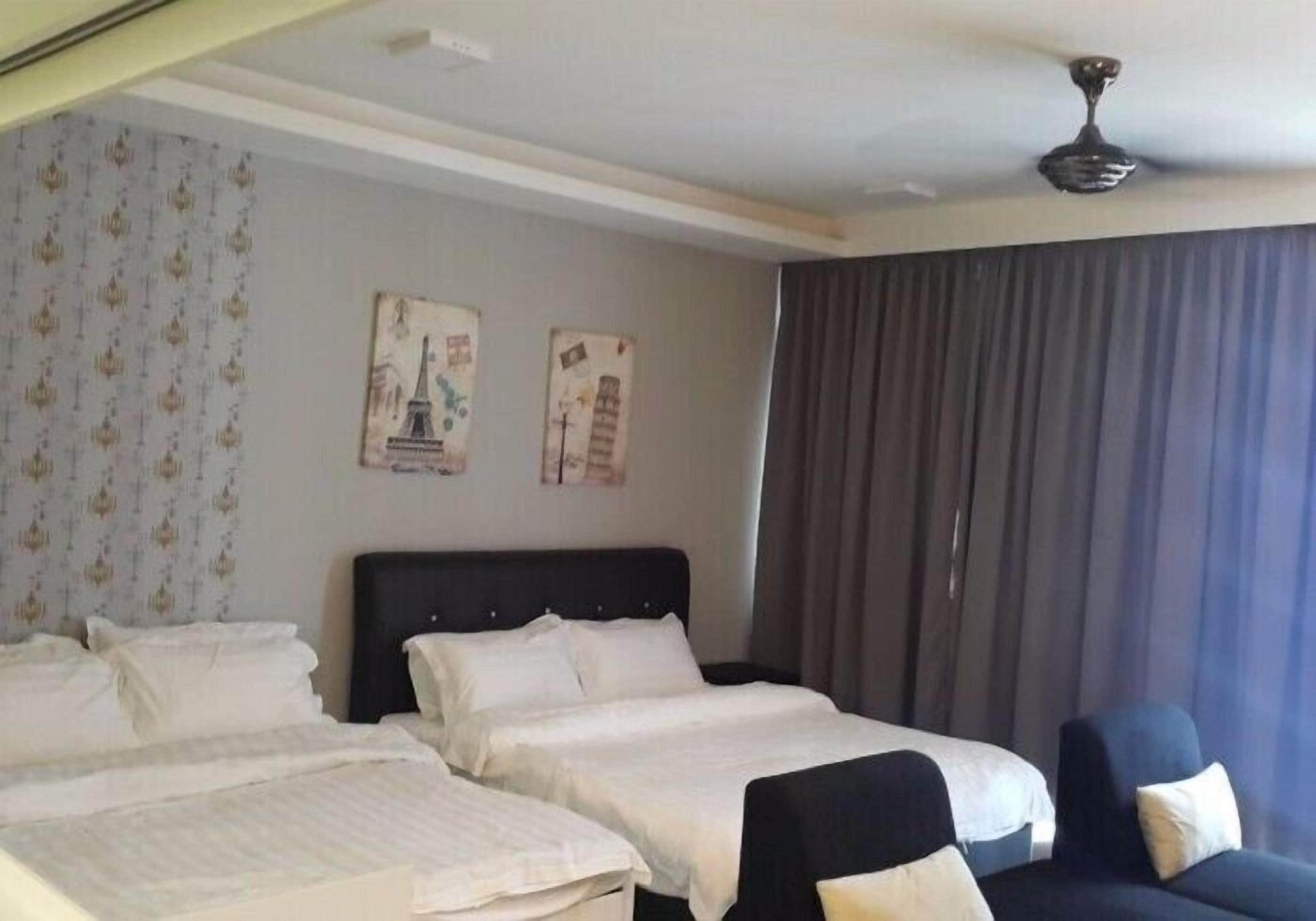 A hotel room with two beds, a black headboard, a ceiling fan, and a large window with curtains.
