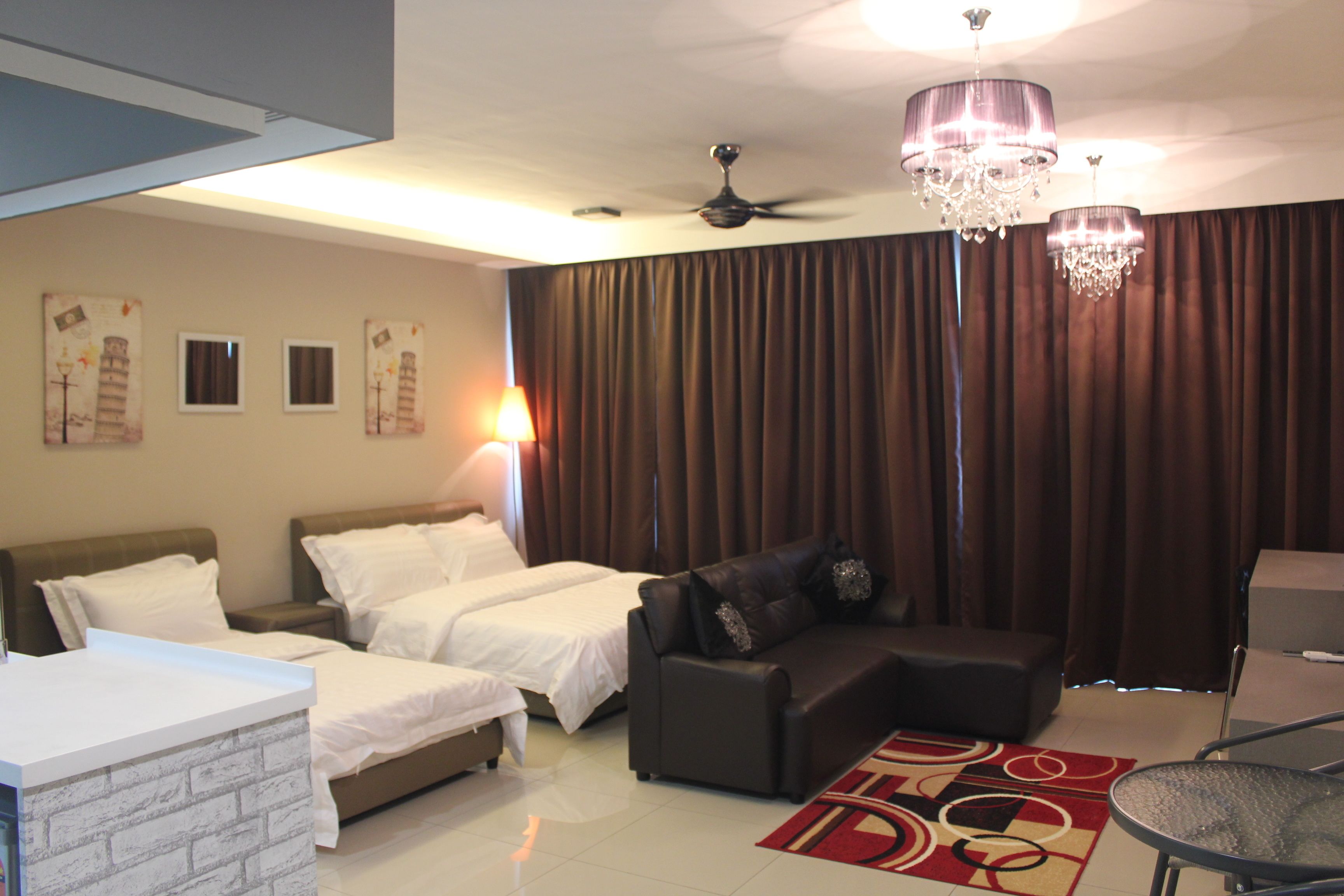 A hotel room with two beds, a sofa, a small table, a chandelier, and curtains.