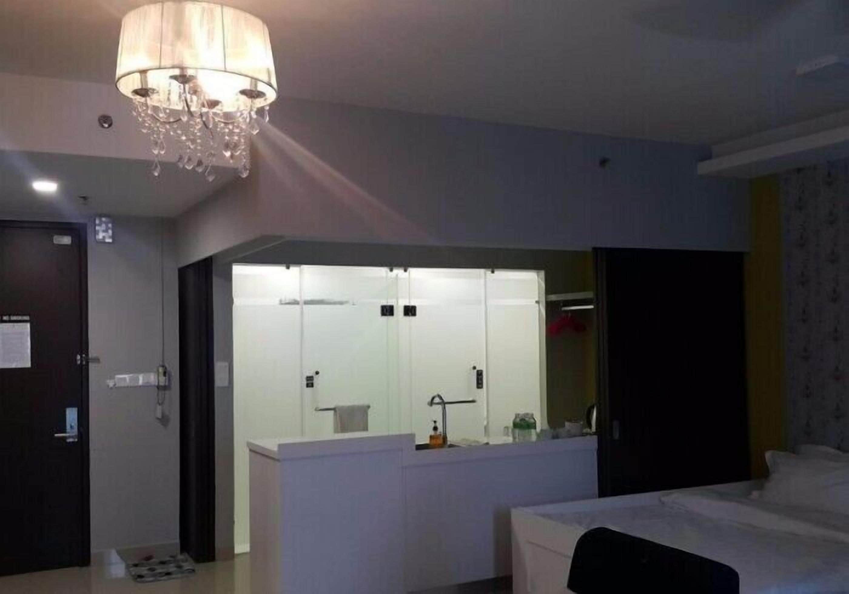 Una habitación de hotel con un espejo grande, una cama, una mesita de noche y un candelabro.