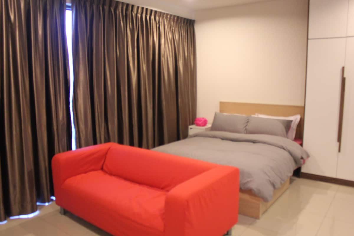 Une chambre à coucher avec un lit, une table de chevet, un canapé rouge et une armoire.