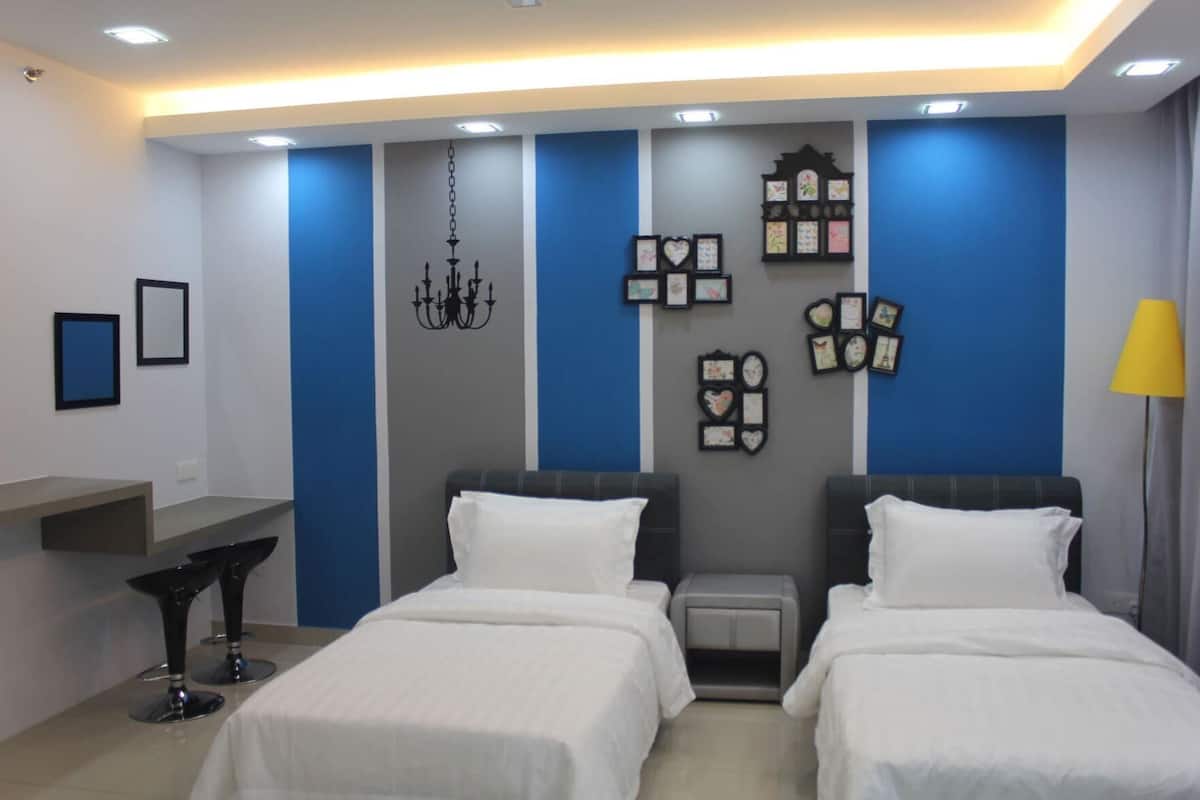 Une chambre d’hôtel avec deux lits, un lustre, des cadres photos accrochés au mur et une table de chevet.