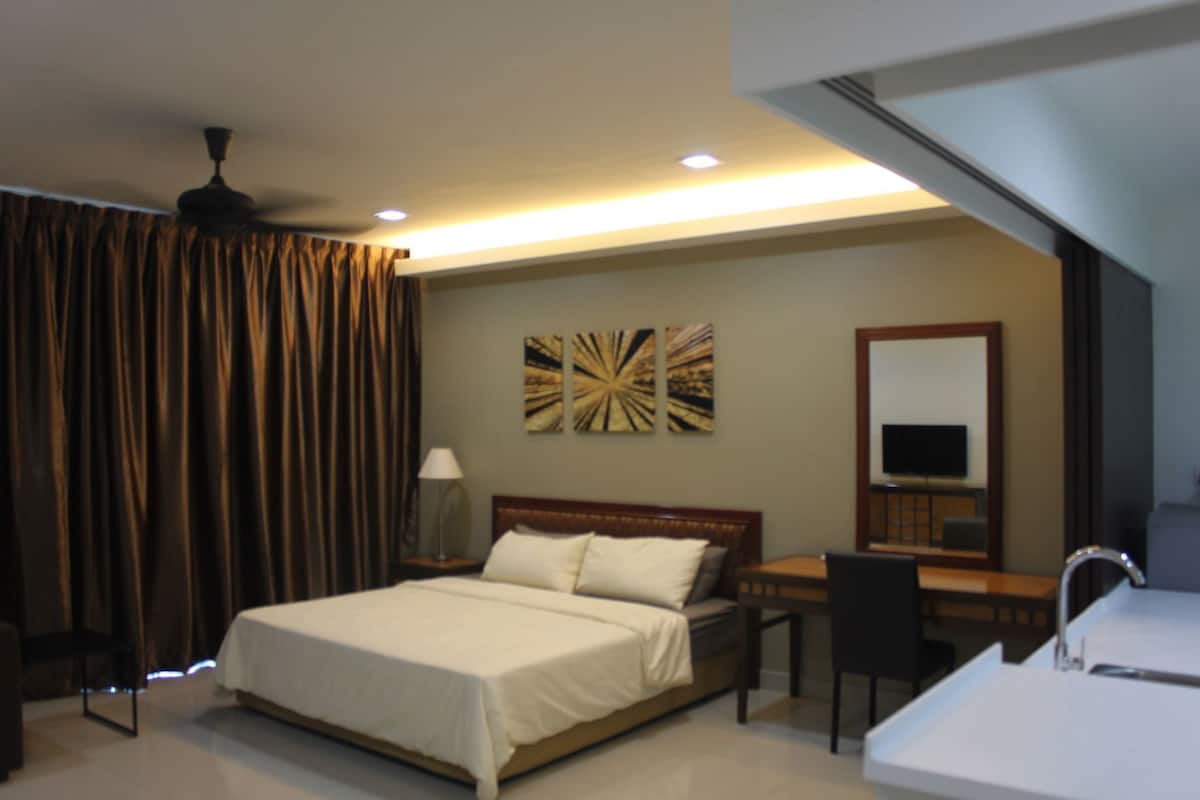 Une chambre d’hôtel avec un lit, un bureau, une chaise et un grand miroir.