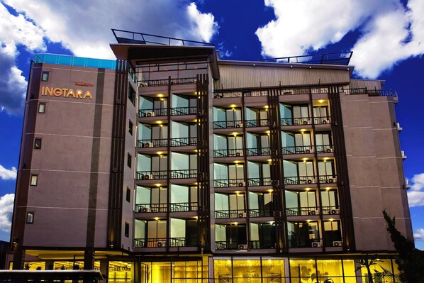 A multi-story hotel with a modern design, featuring balconies on each floor and a prominent entrance with glass doors.