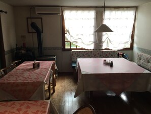 A dining area with two tables, a bench, and a window with curtains. - Friendly Inn People (Fujikawaguchiko)