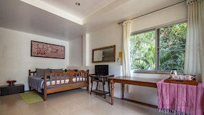 A room with a bed, a desk, a chair, a TV, and a window with a view of greenery. - Good Time Sports Village (Ko Mak)