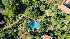 An aerial view of a property with a swimming pool surrounded by lush greenery and palm trees. - Good Time Sports Village (Ko Mak)