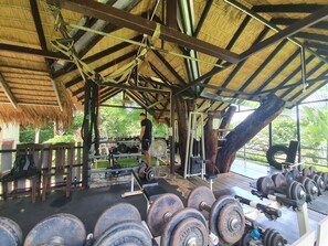 A covered outdoor gym with various exercise equipment, including dumbbells and benches. - Good Time Sports Village (Ko Mak)