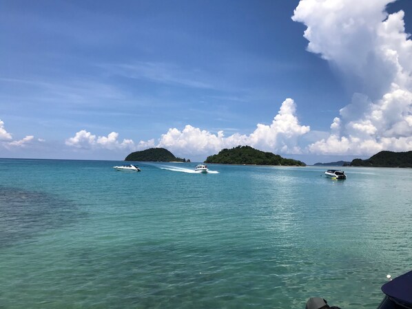 A clear view of a tropical beach with boats on the water and a small island in the background. - Good Time Sports Village (Ko Mak)