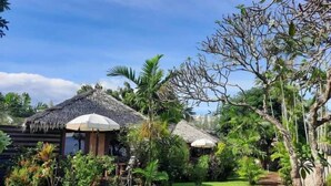 A tropical resort with thatched-roof huts, lush greenery, and a clear sky. - Bann Pae Cabana (Rayong)