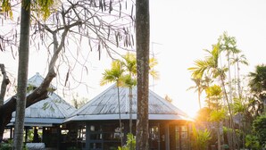 A rustic building with a metal roof, surrounded by palm trees and other tropical vegetation. - Bann Pae Cabana (Rayong)