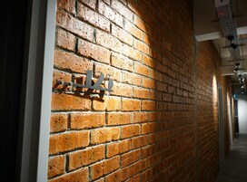 Un pasillo con pared de ladrillo y un letrero metálico que indica la habitación 125.