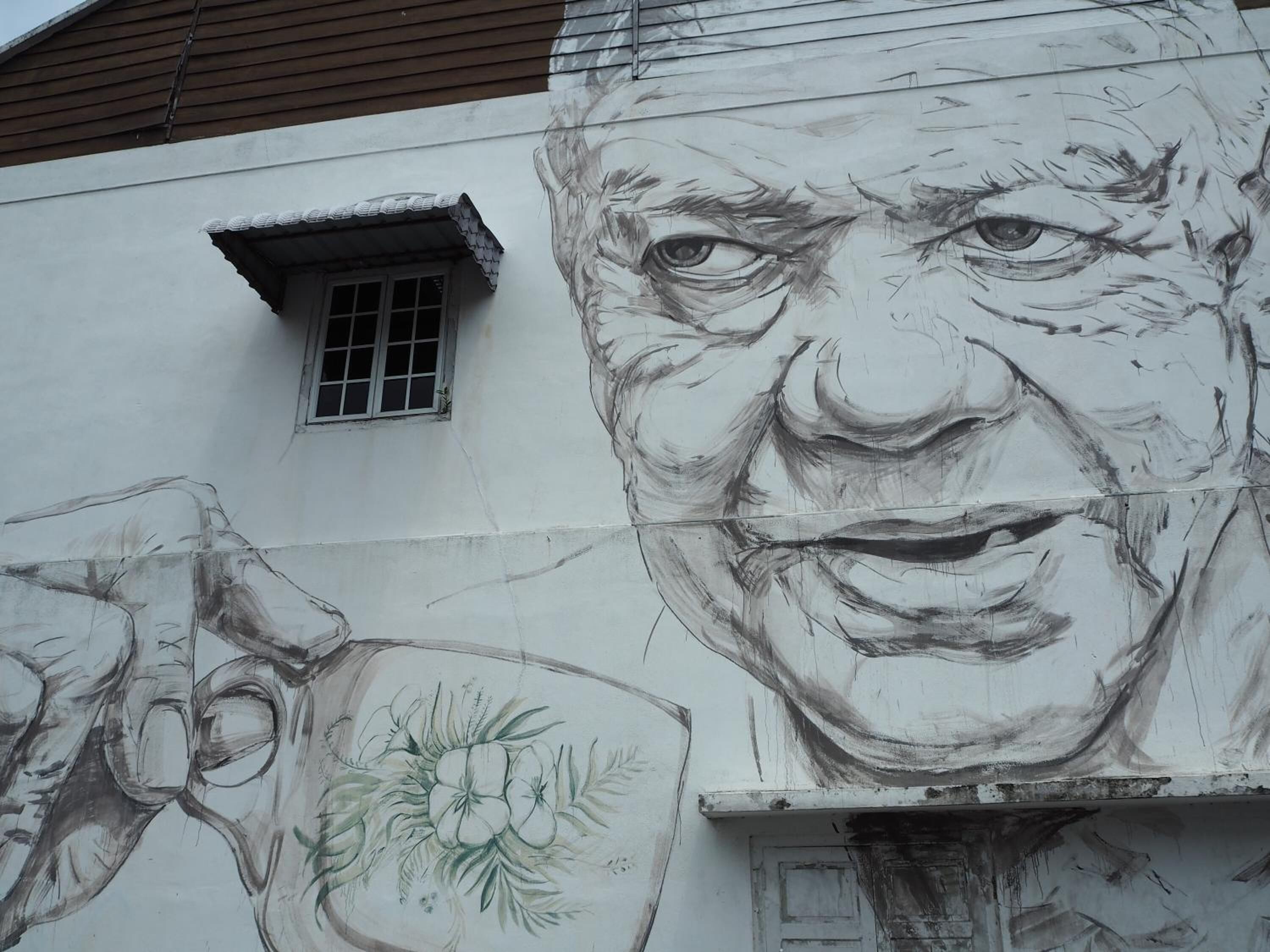 A building with a large mural featuring a face and floral elements.