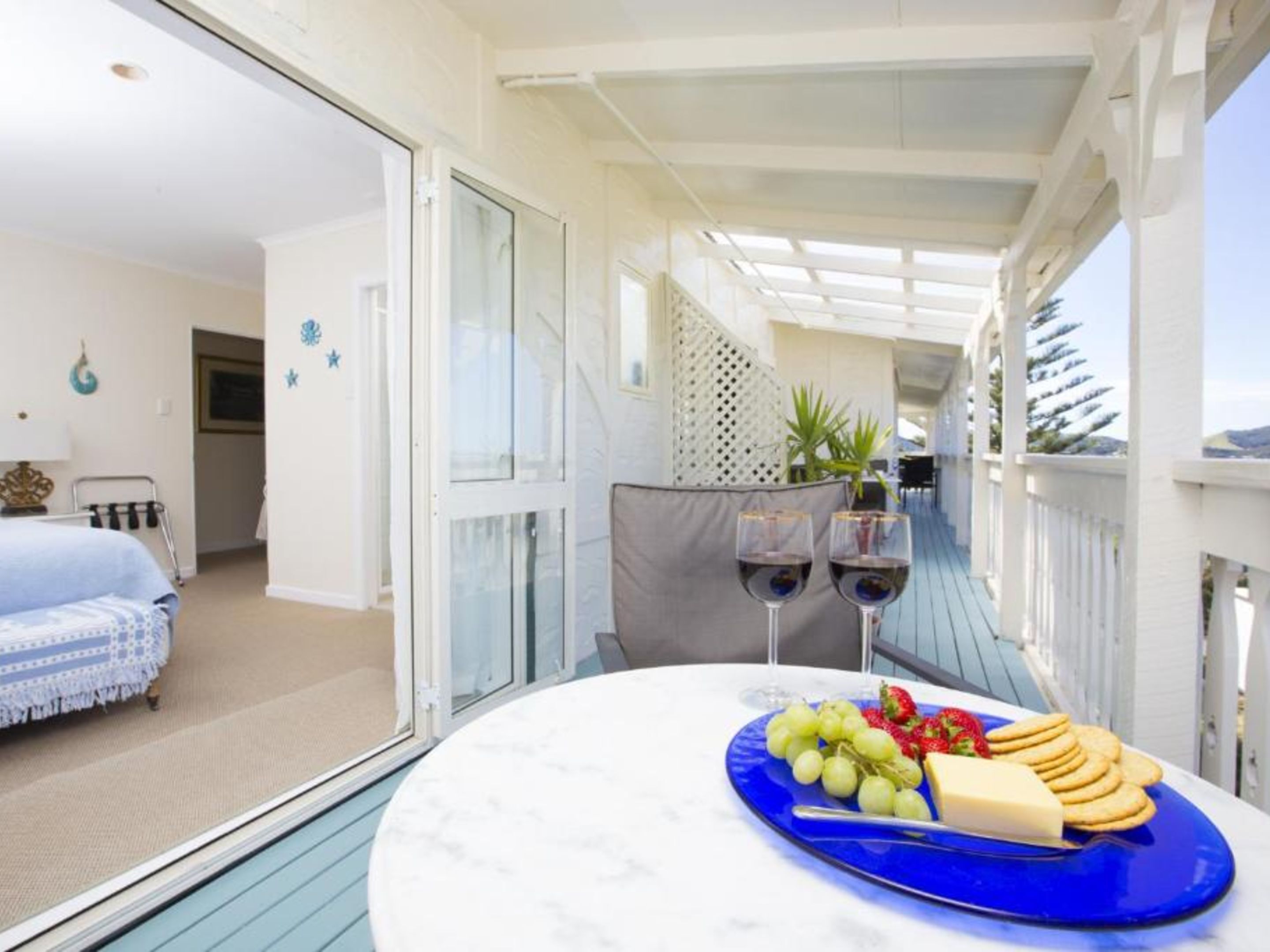 A balcony with a table set for a meal, a bed, and a view of the sea.