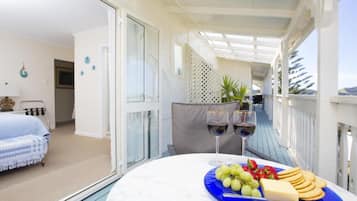 A balcony with a table set for a meal, a bed, and a view of the sea.