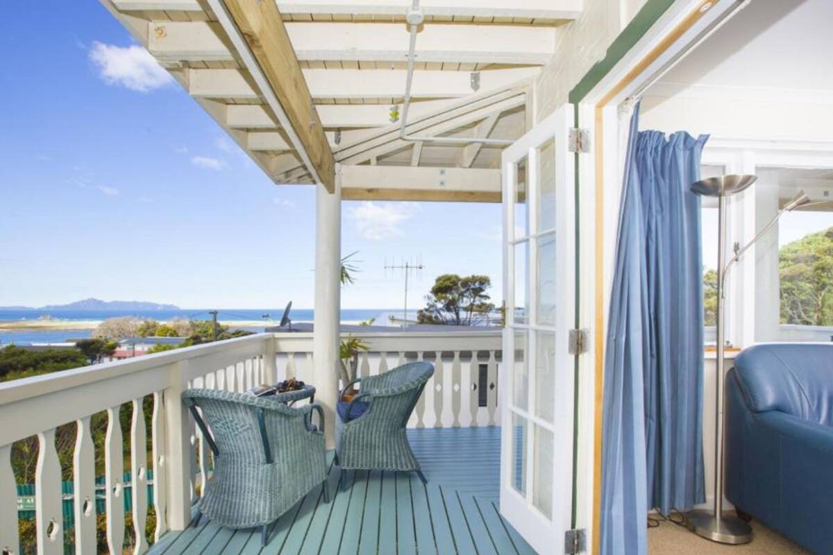 Ein Balkon mit Blick auf das Meer, zwei Korbstühle und ein blaues Sofa.