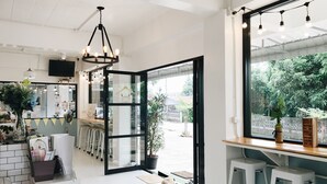 A modern interior with a glass door leading outside, a hanging light fixture, and a small dog on the floor. - Baan Nuk Anong (Chiang Rai)