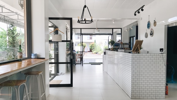 A modern kitchen with white tiled backsplash, bar stools, and a central island. - Baan Nuk Anong (Chiang Rai)